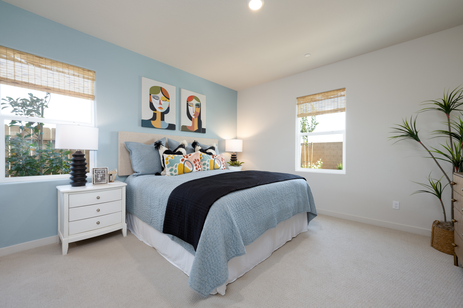 A bedroom with a bed and a plant.