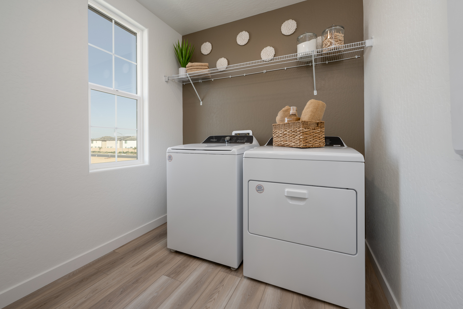 A room with white cabinets and a white shelf with baskets on it.