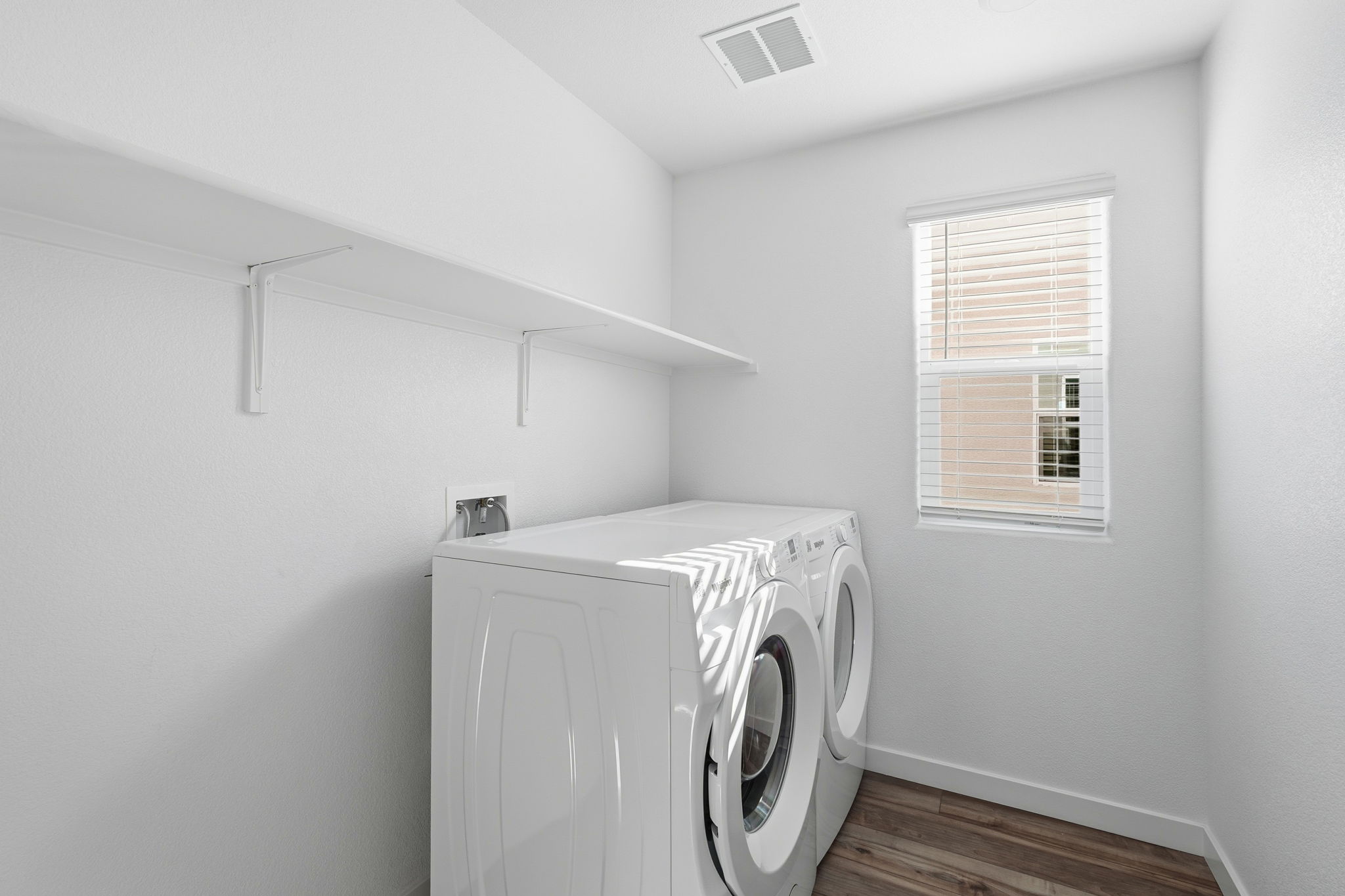 A white room with a washing machine and a window.