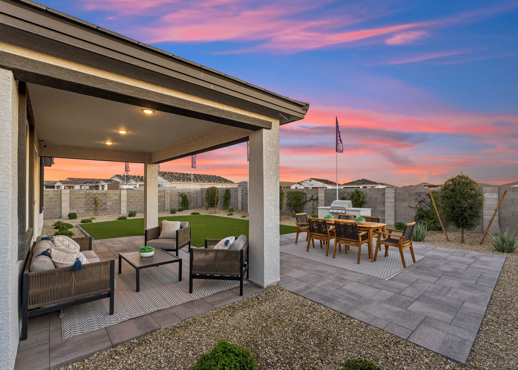 A patio with a table and chairs and a view of a sunset.