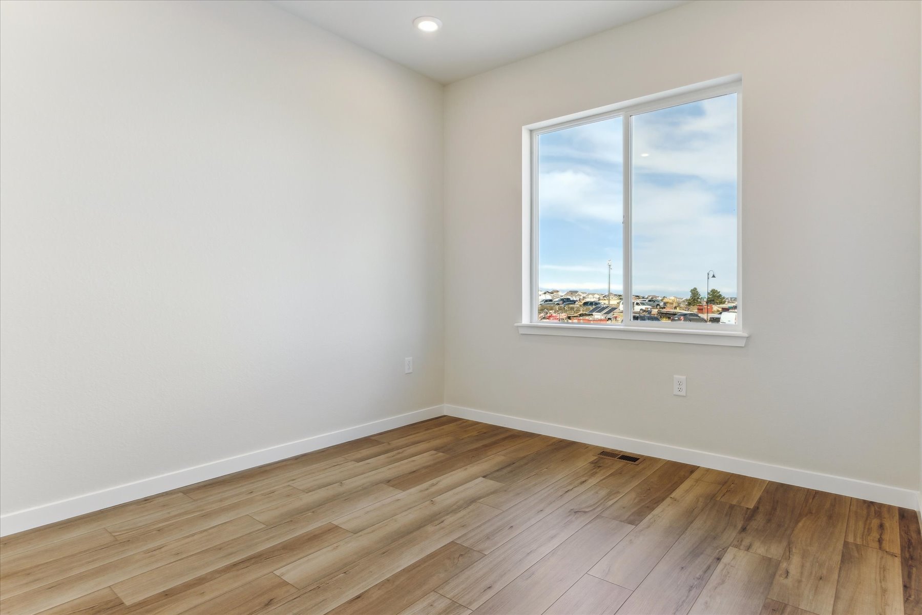 A room with a window and a wood floor.