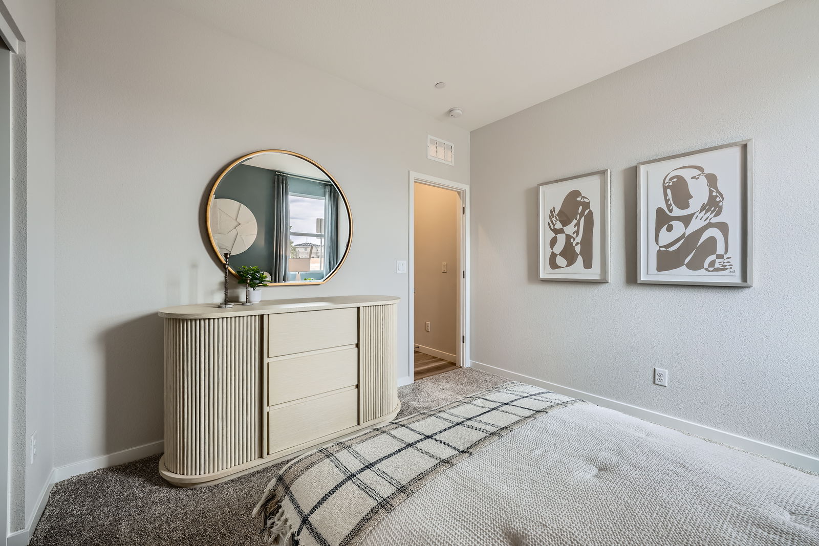 A room with a mirror and a dresser.