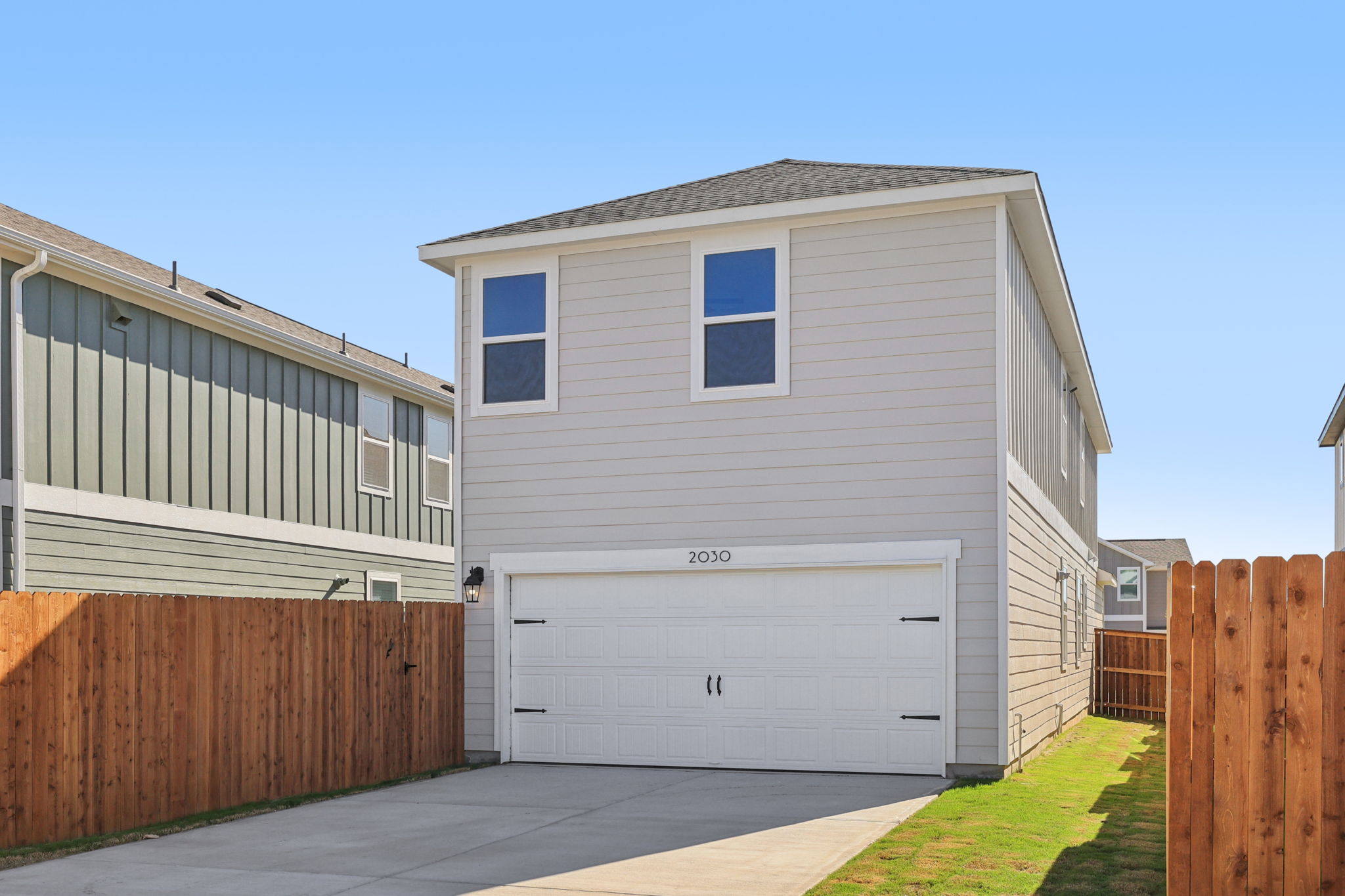 A white garage next to a wooden fence.