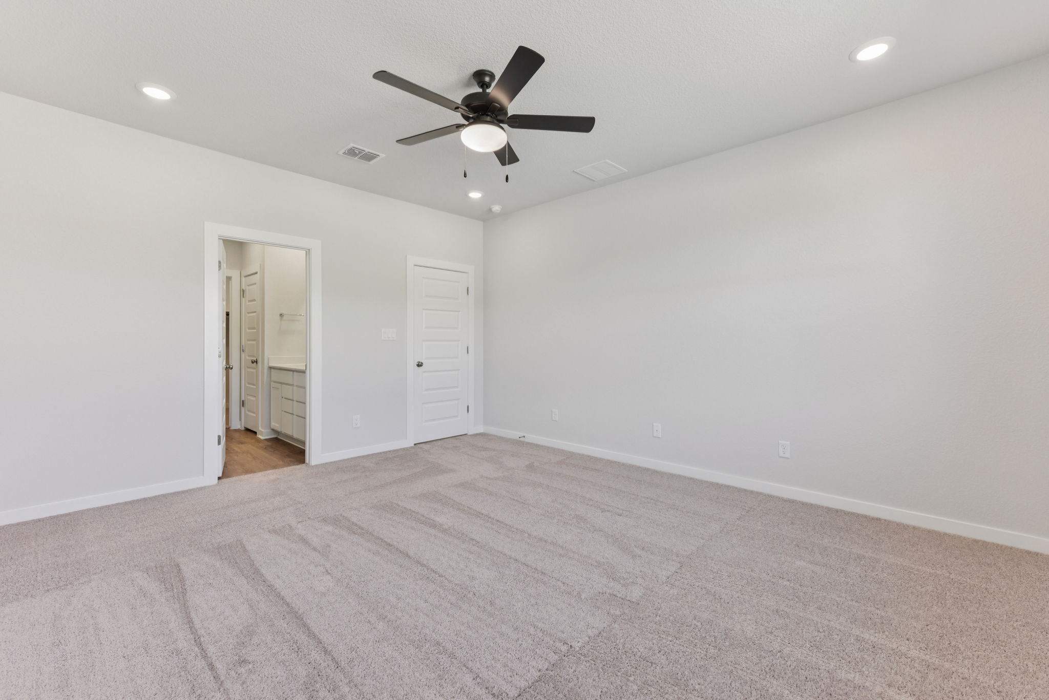 A room with a ceiling fan and a carpet.
