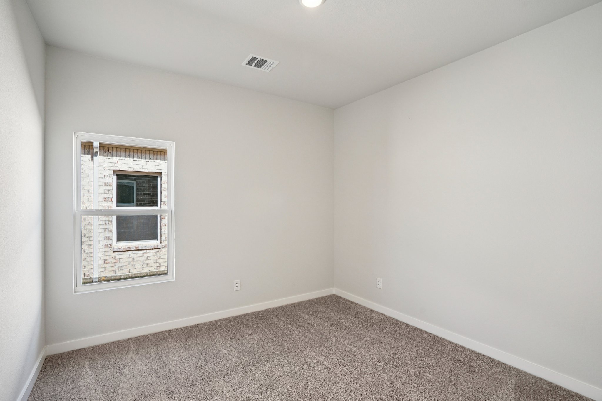 A room with a window and a rug.