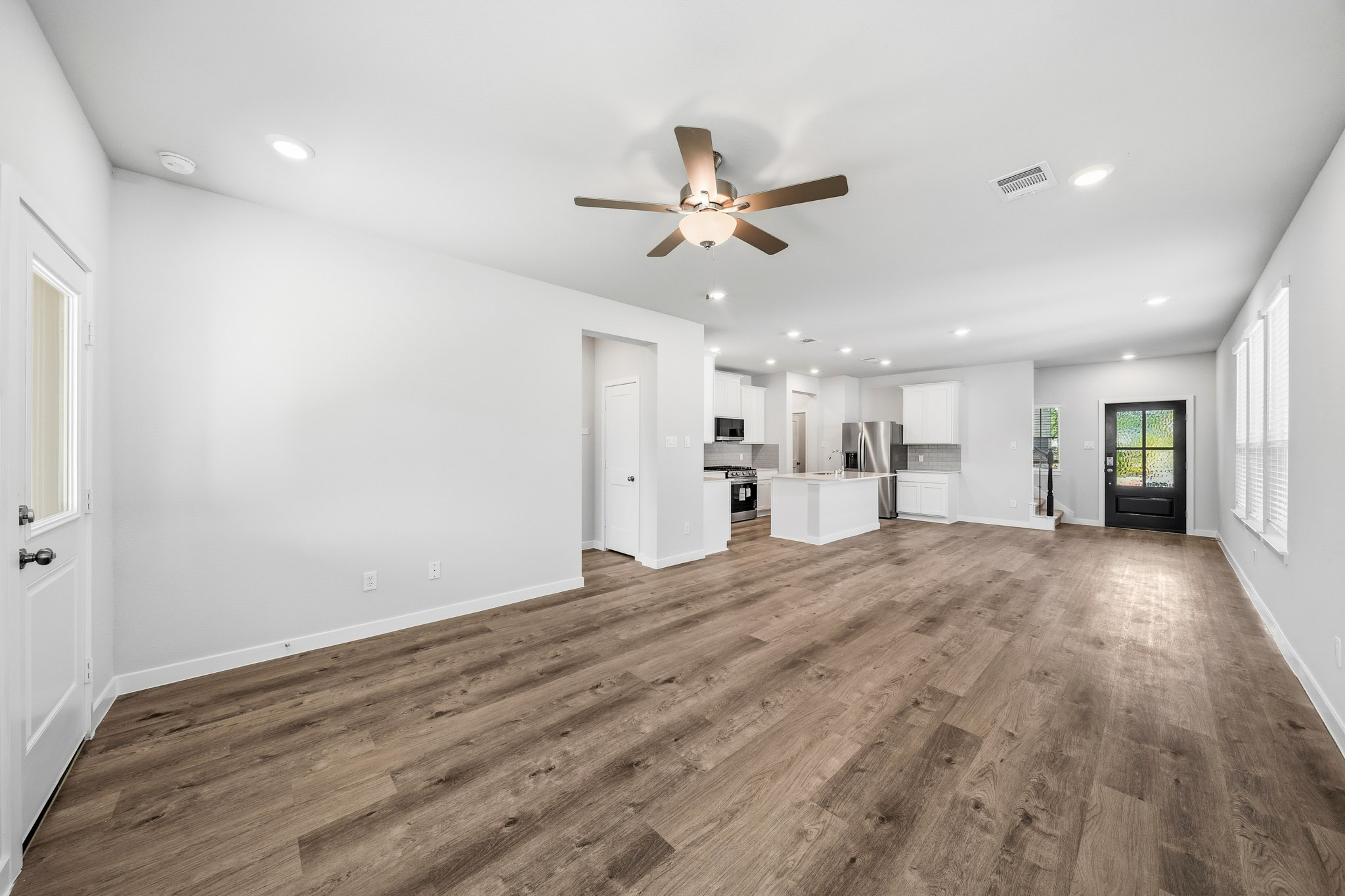 A large empty room with a wood floor and a ceiling fan.