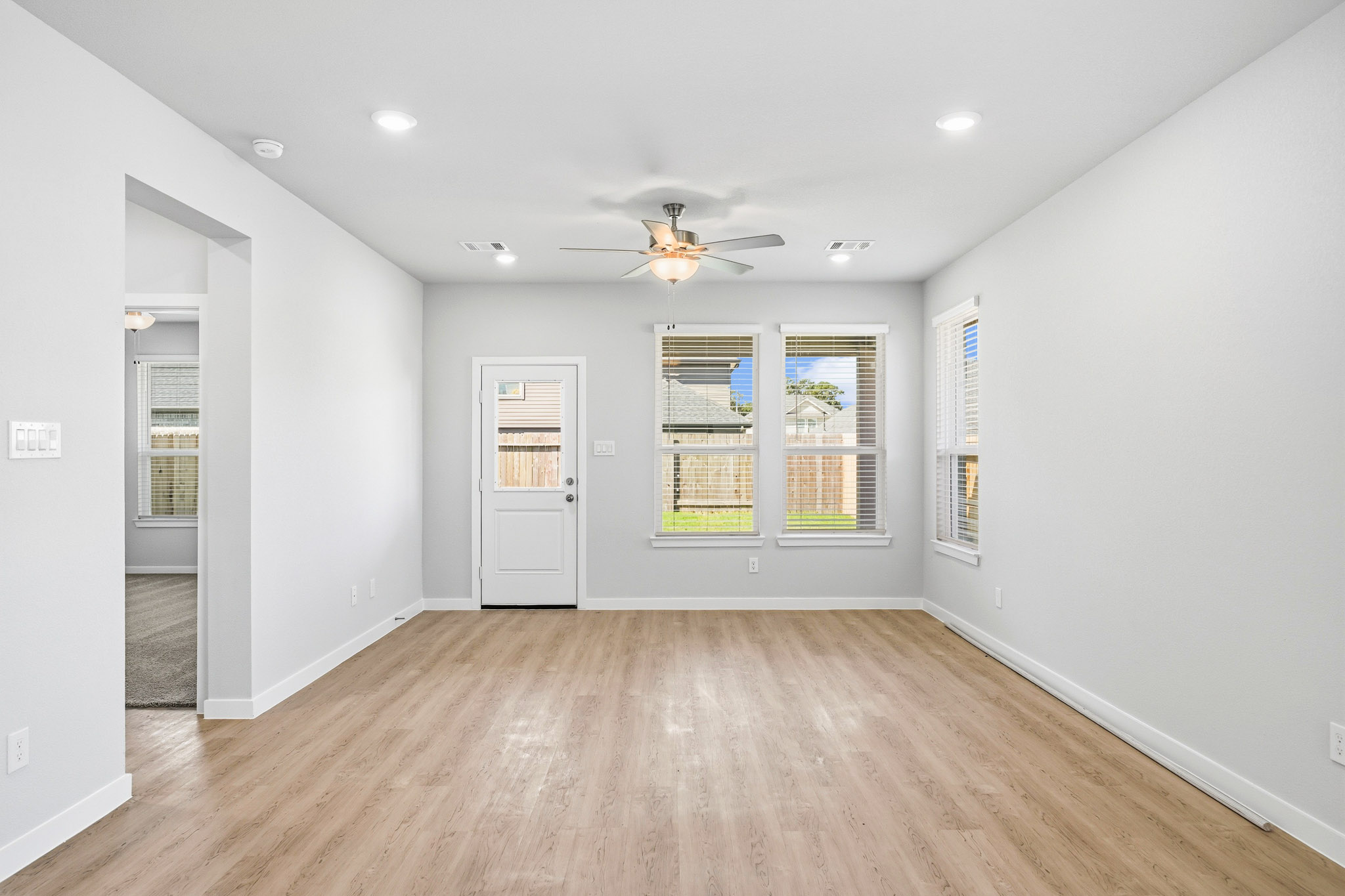 A room with a wood floor and a wood floor with a ceiling fan.