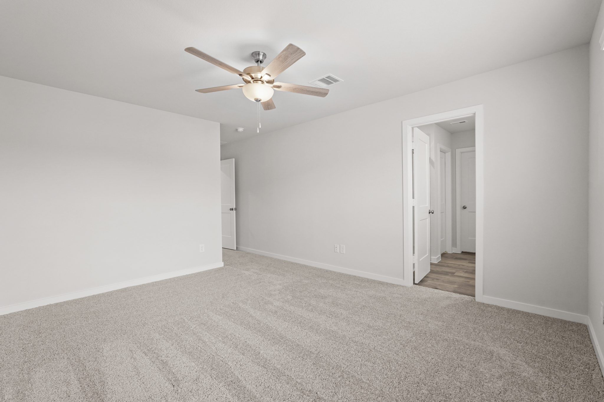 A room with a ceiling fan and white walls.