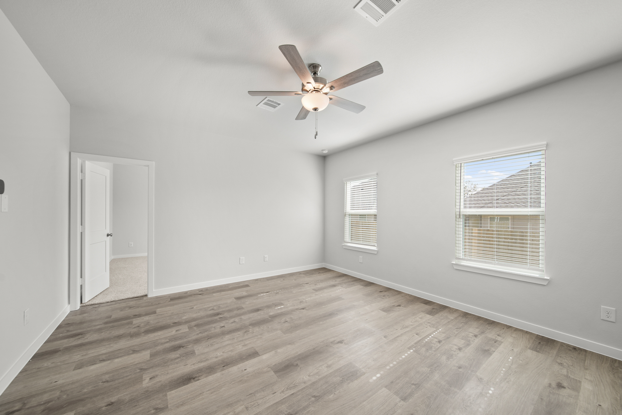 A room with a ceiling fan and wood floor.