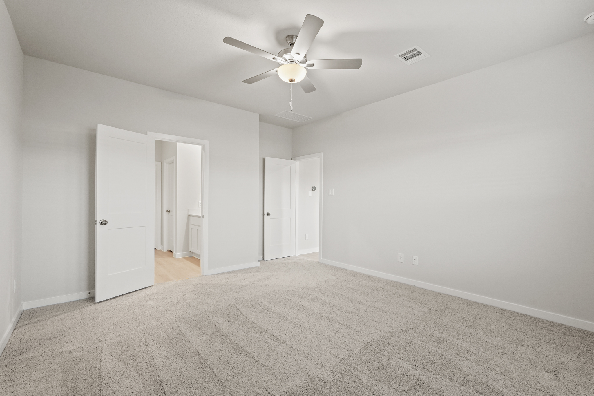 A room with a ceiling fan and white doors.