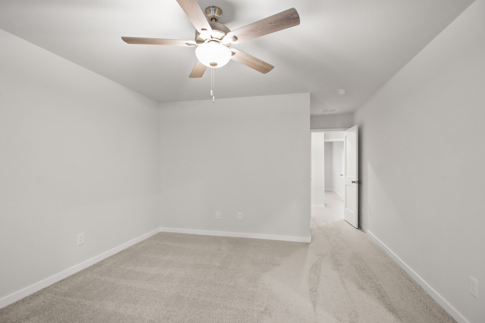 A room with a ceiling fan and a door.