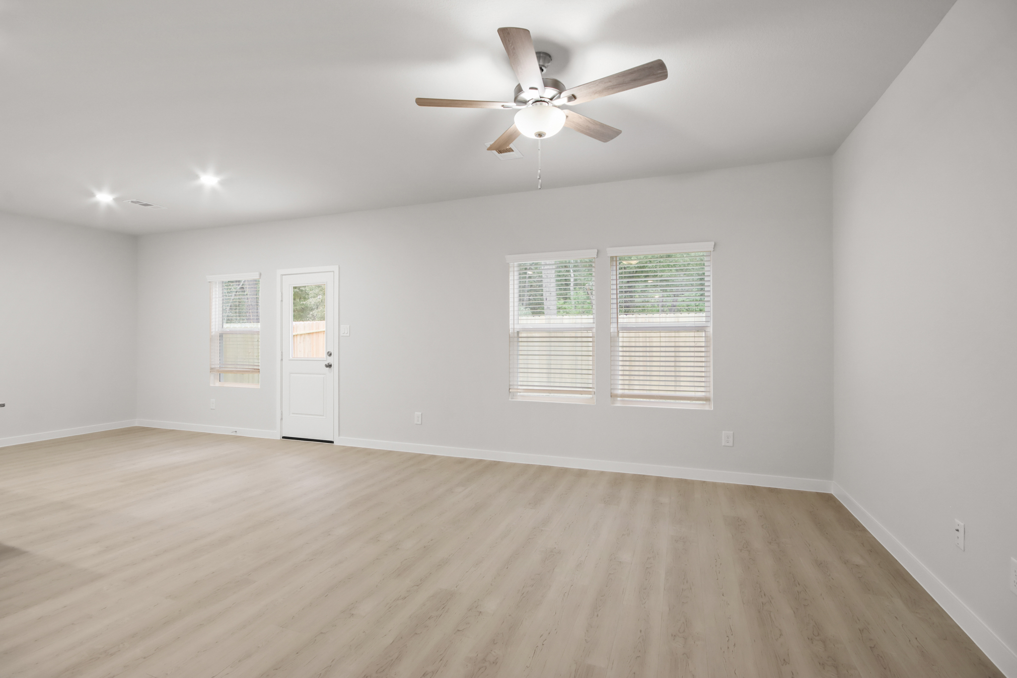 A room with a ceiling fan and a wood floor.