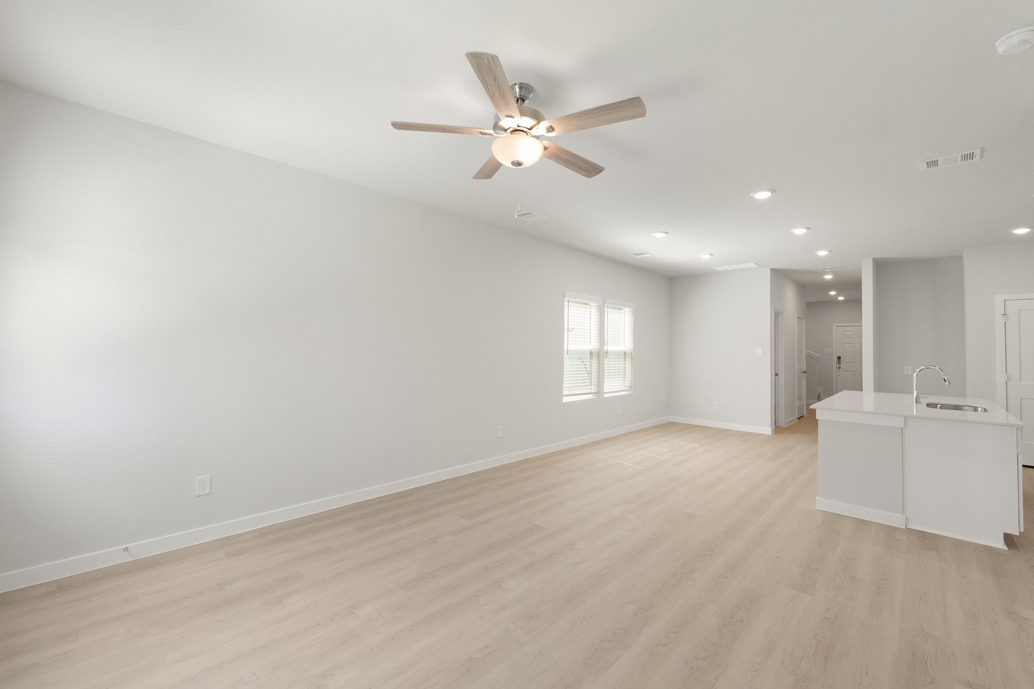 A large empty room with a ceiling fan and a wood floor.