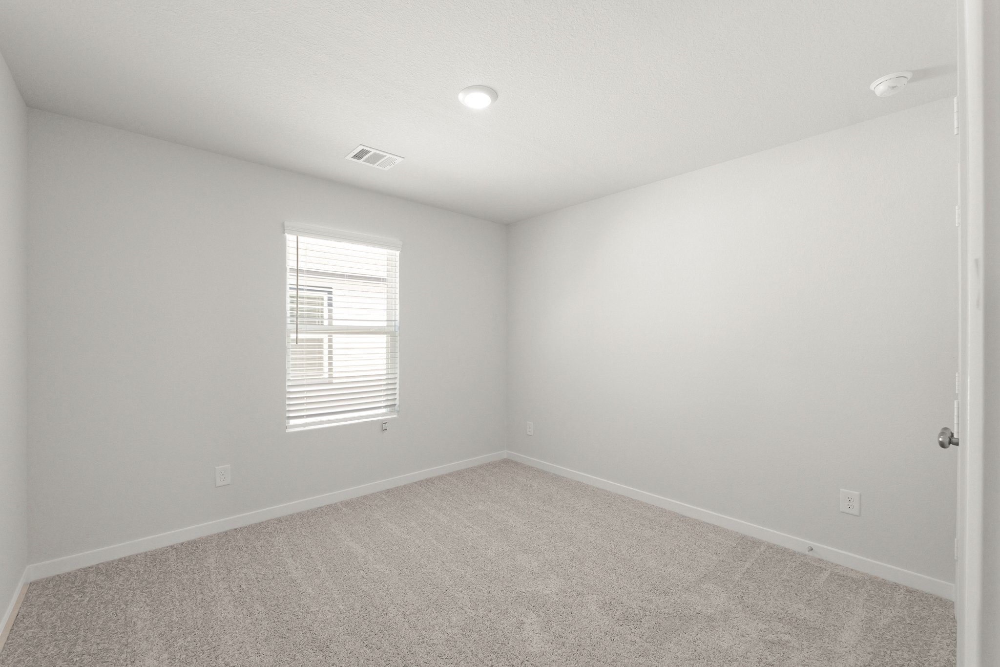 A room with a carpet and a window.