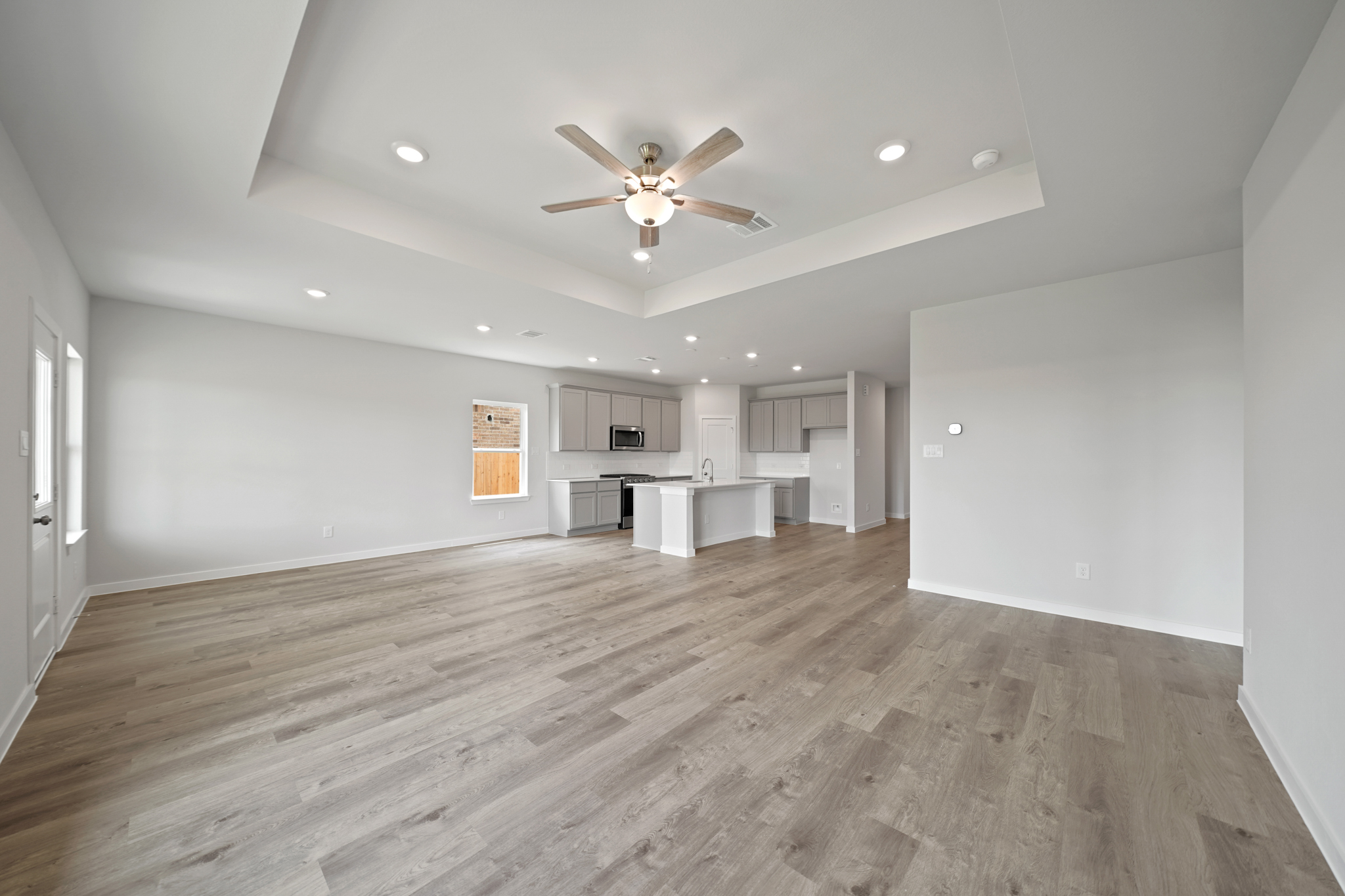 A large empty room with a wood floor and a ceiling fan.