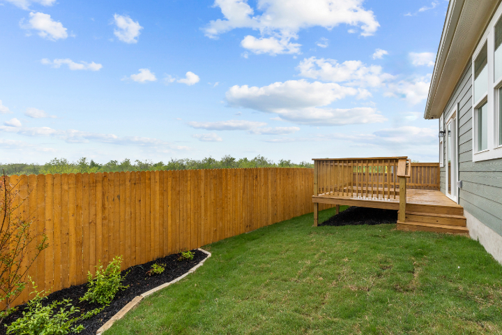A fenced in yard with a house and a wood gate.