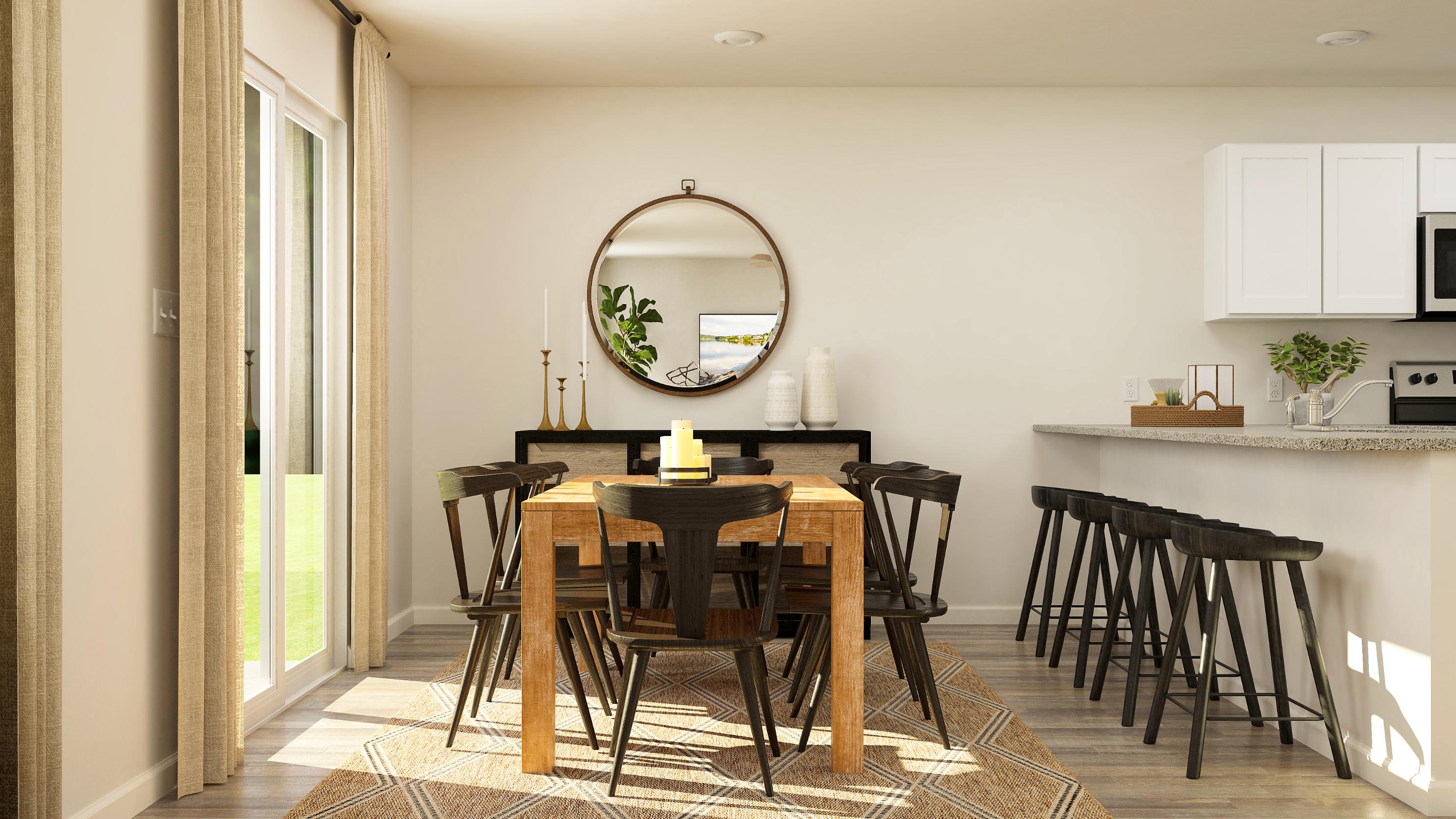 A dining room with a round mirror.